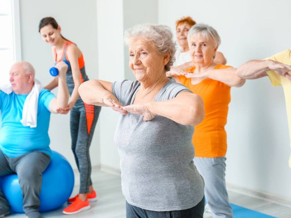 Group of older mature people lifting weights in the gym