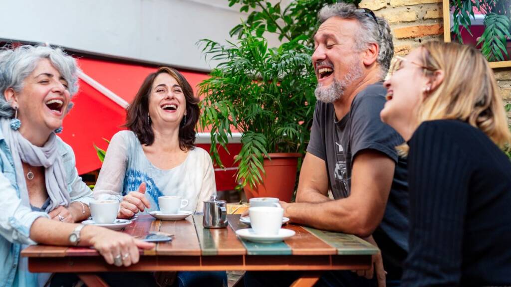 a group of people at a coffee shop laughing. Several age groups and sex